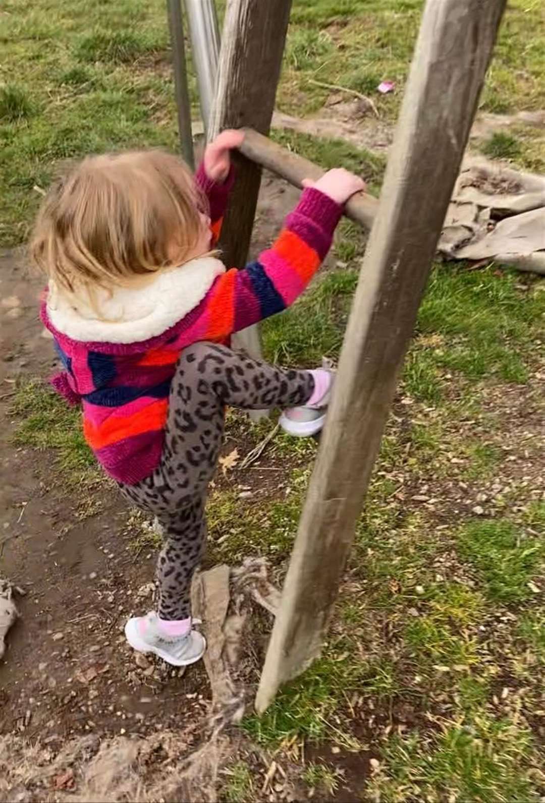 Stretching past a missing rung on the ladder on a climbing frame.
