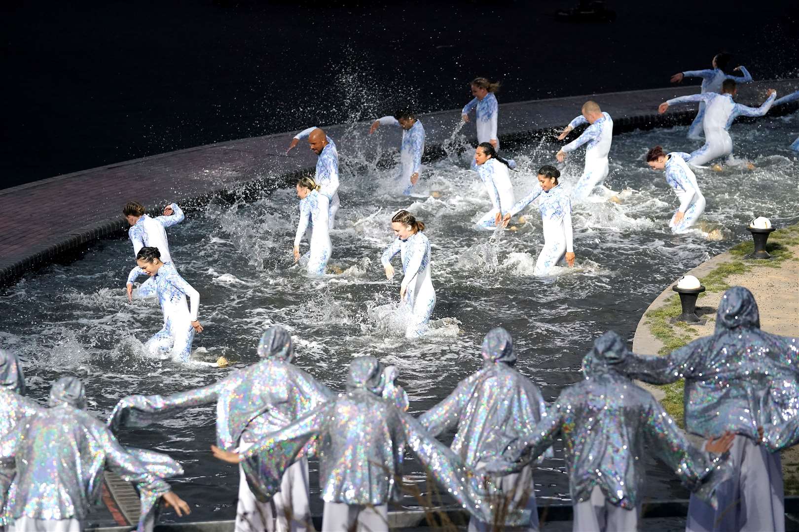 Performers dance on a water-soaked stage (Zac Goodwin/PA)