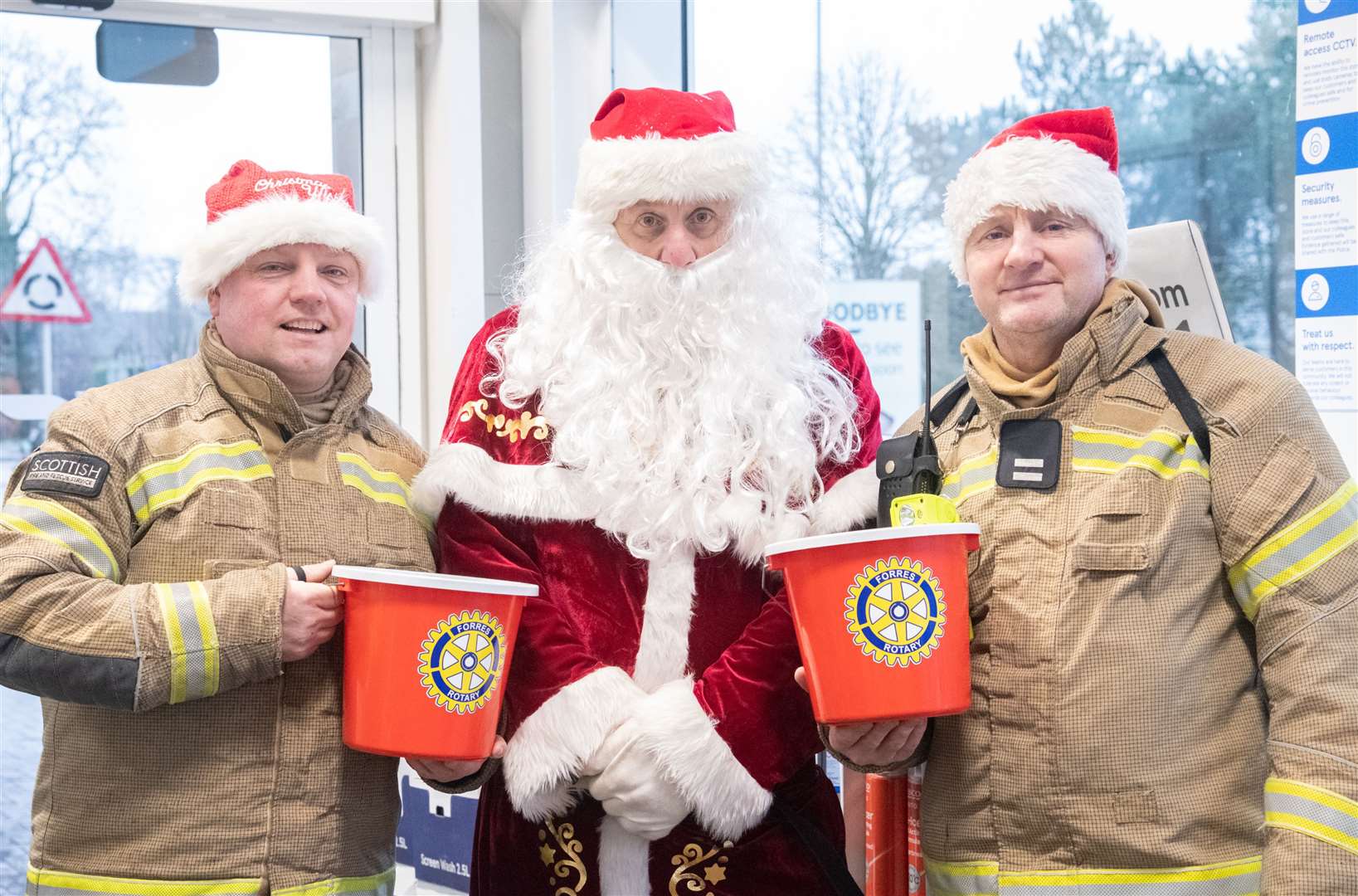 Forres firefighters Stewart Fraser (left) and David Raeburn (right) join Santa at the Forres Tesco.