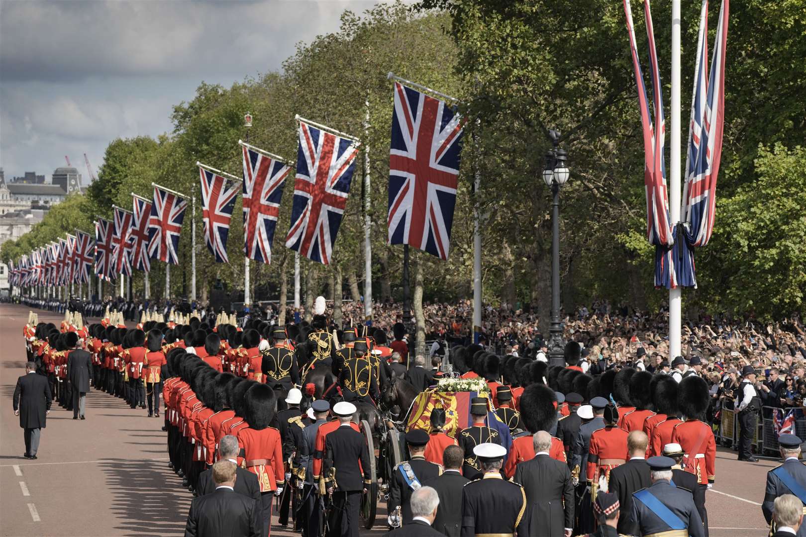 The coffin of Queen Elizabeth II, draped in the Royal Standard, is carried on a horse-drawn gun carriage of the King’s Troop Royal Horse Artillery during the ceremonial procession from Buckingham Palace to Westminster Hall (Vadim Ghirda/PA)