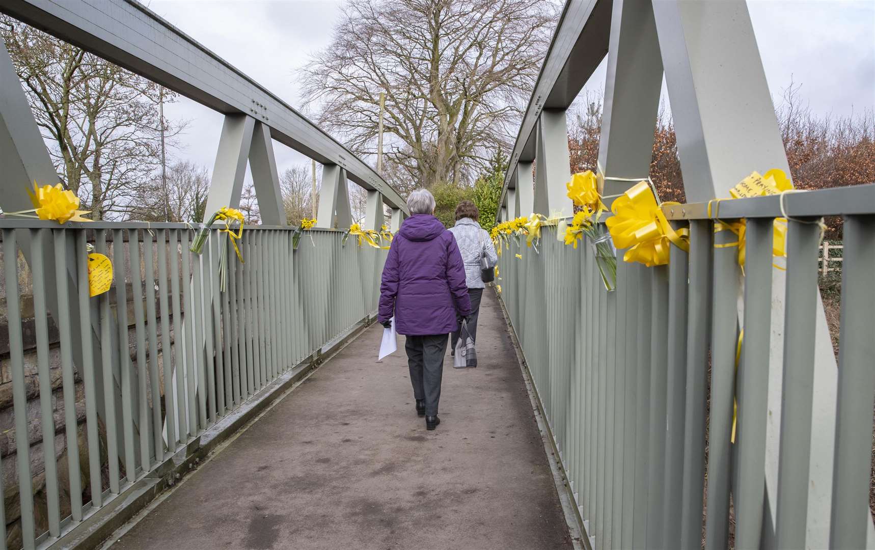 People walk past yellow ribbons tied to a bridge over the River Wyre (Jason Roberts/PA)