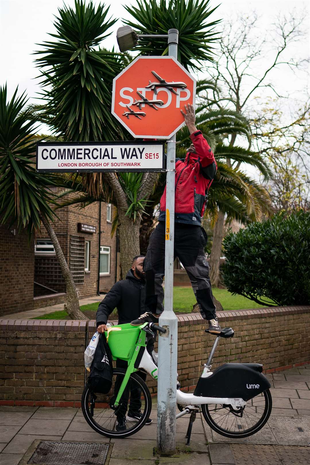 A man stands on a bike to remove a piece of art work by Banksy (Aaron Chown/PA)