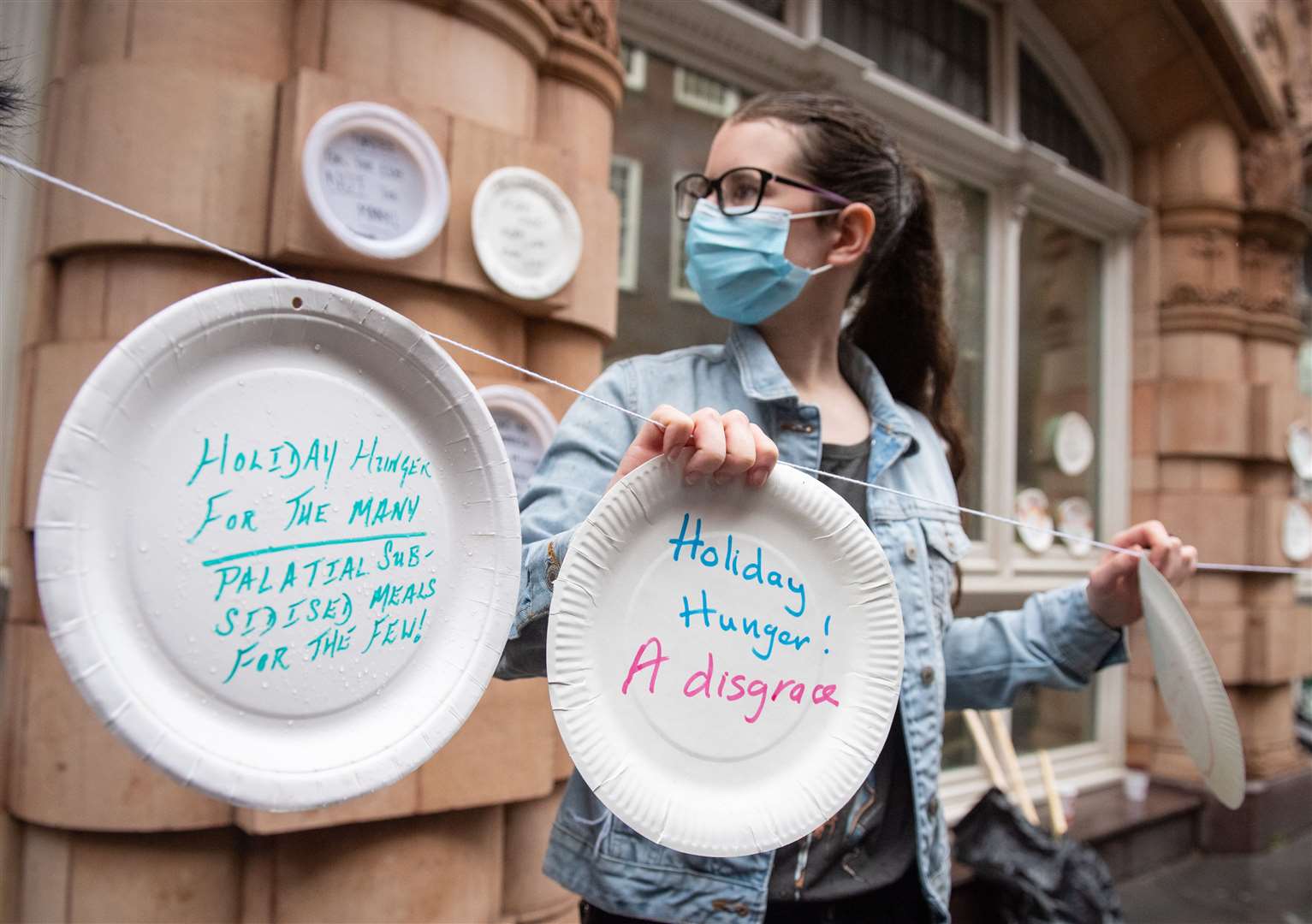 Protestors hang up paper plates carrying slogans calling for the Government to extend the free school meals provision (Dominic Lipinski/PA)