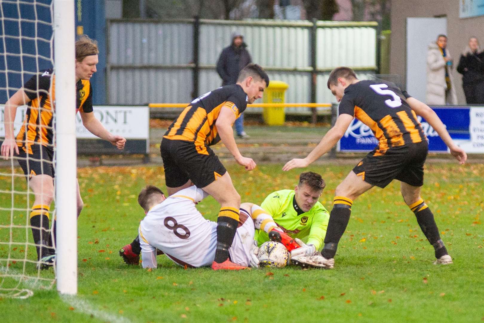 Forres' Jack Grant (#8) is the attention of the Huntly defence and goalkeeper Tom Ritchie. Picture: Daniel Forsyth..