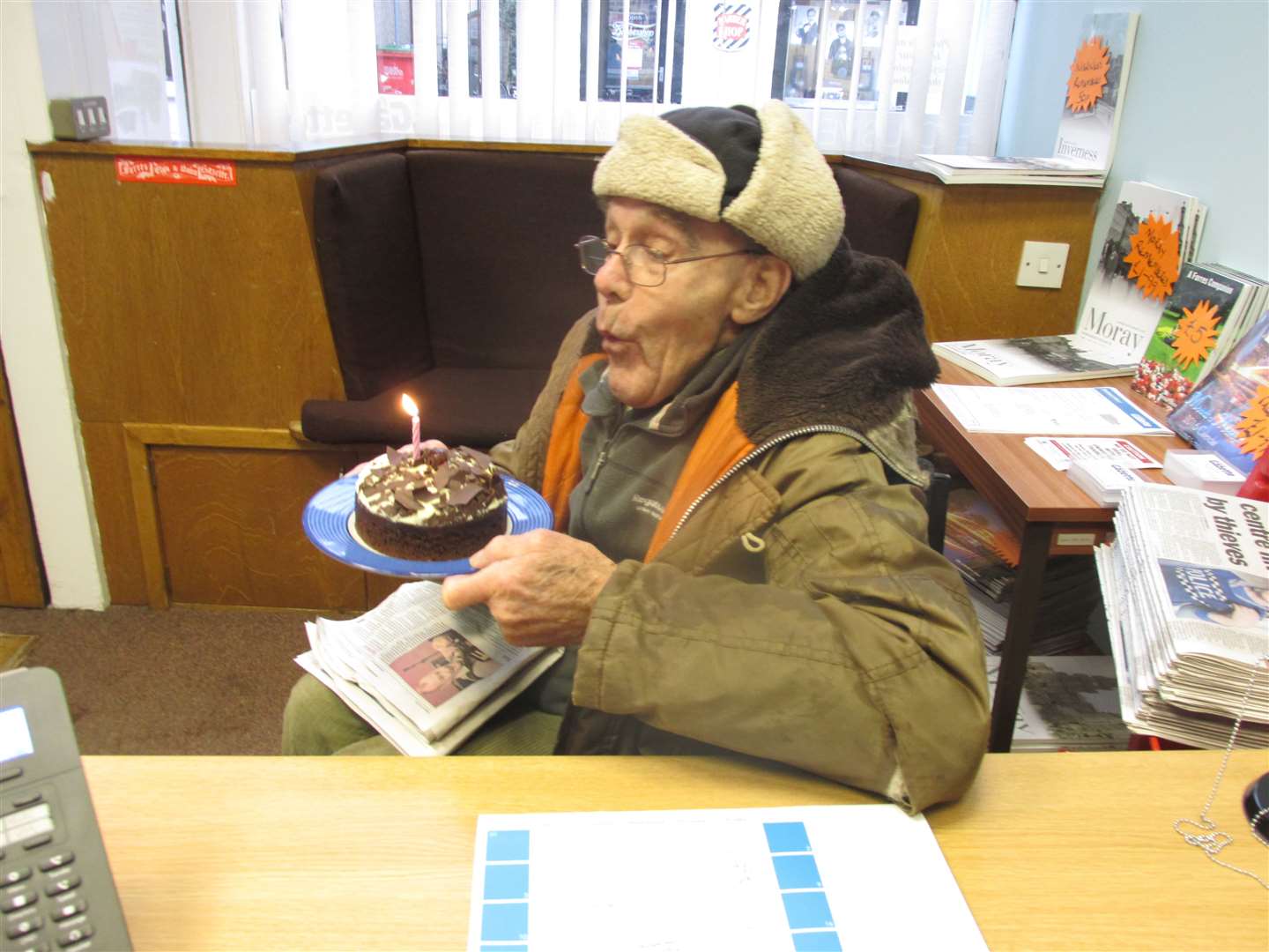 Les Clyne in the Forres Gazette office blowing out a candle on his 90th birthday.