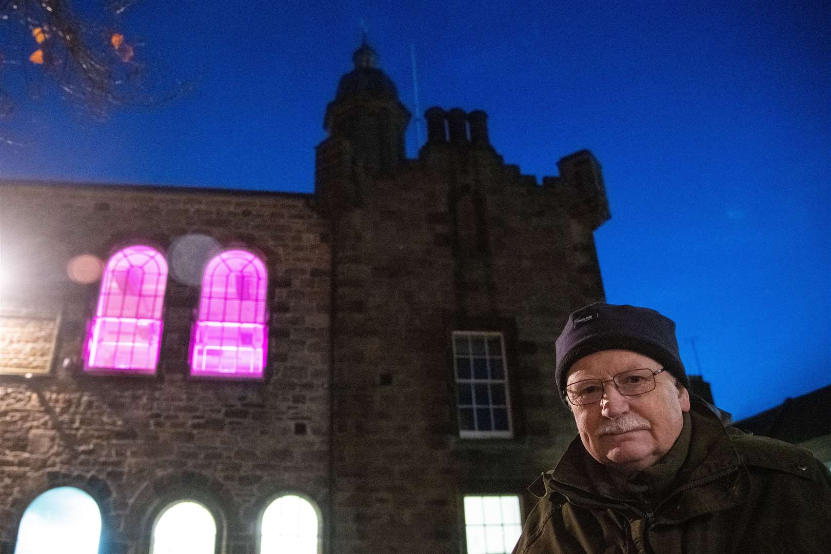 Bob James with a room inside the Tolbooth lit up purple for polio.
