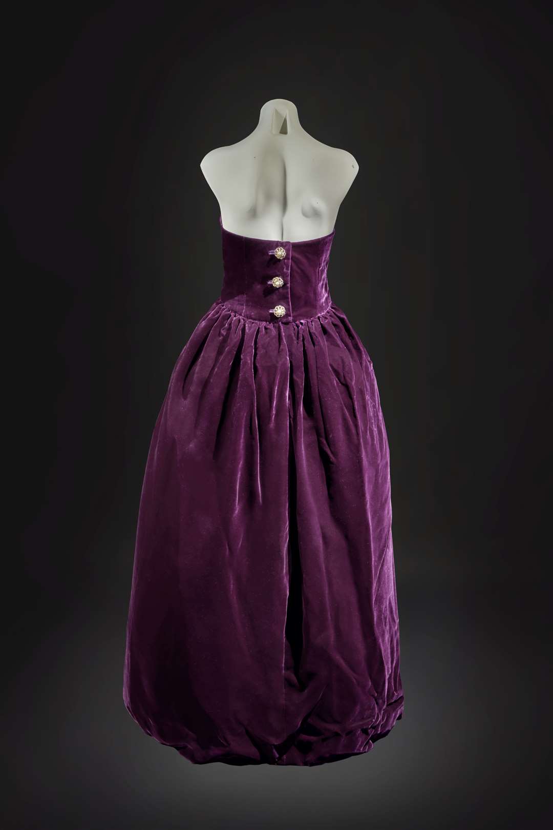 The ball dress is of deep aubergine silk velvet, with a tulip-shaped stiffened skirt, augmented by three paste buttons at the back (Sothebys/PA)