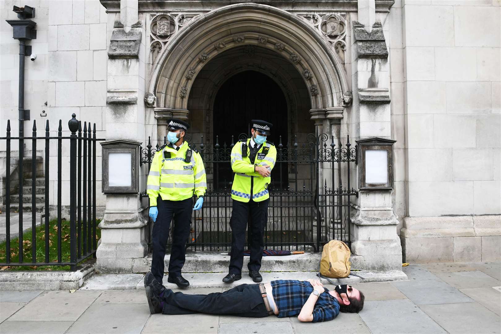 Police stand beside a laying protester during an Extinction Rebellion demonstration in central London (Stefan Rousseau/PA)