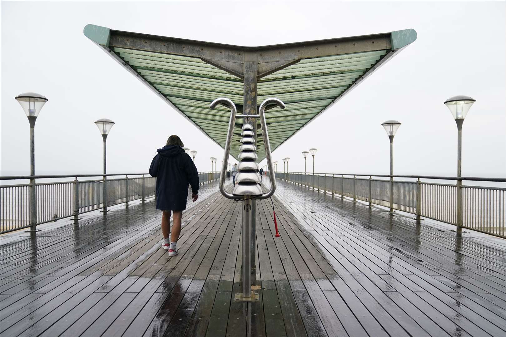 A person makes their way through the rain along Boscombe Pier in Dorset (Andrew Matthews/PA)