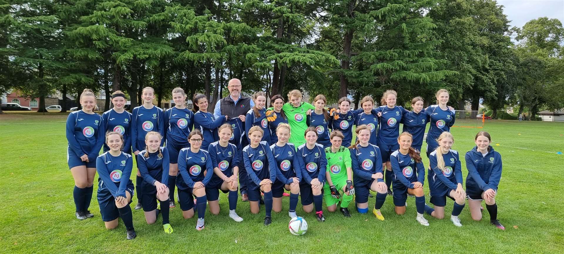AJE director and general manager Graham Alexander with the girls football team donning their new kit.