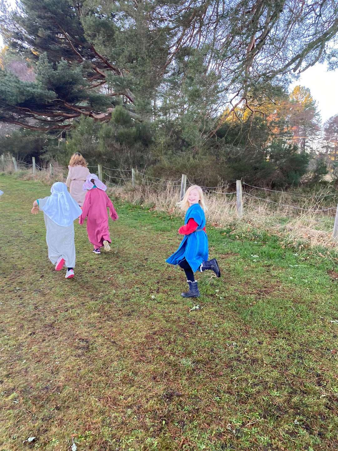 School shepherds including Aila Gibson running to pick up their presents hanging on trees in the woods.