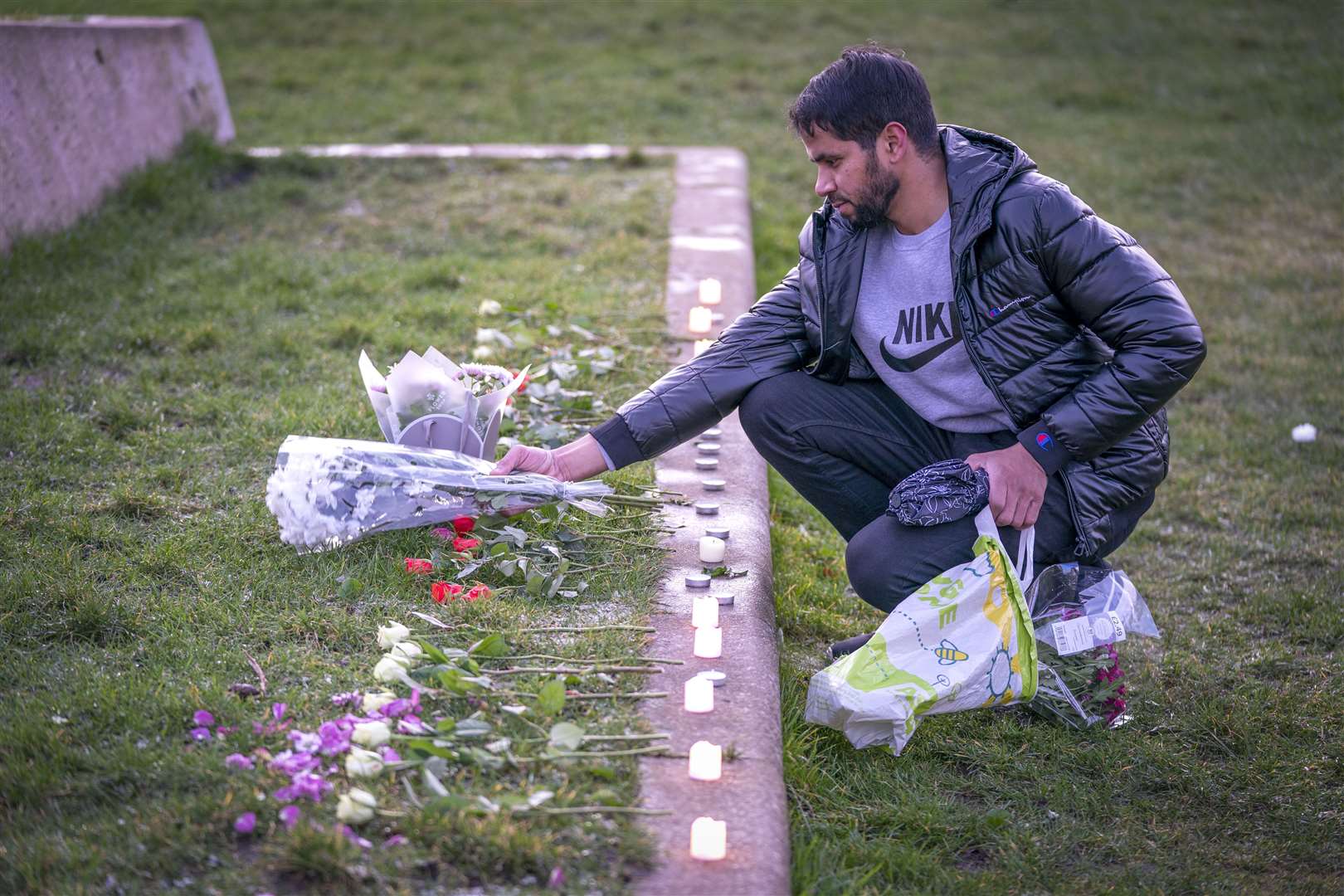 Adnan Hanif, uncle of Fawziyah Javed, lays flowers during a vigil held in honour of Fawziyah who died on Arthur’s Seat (Jane Barlow/PA)