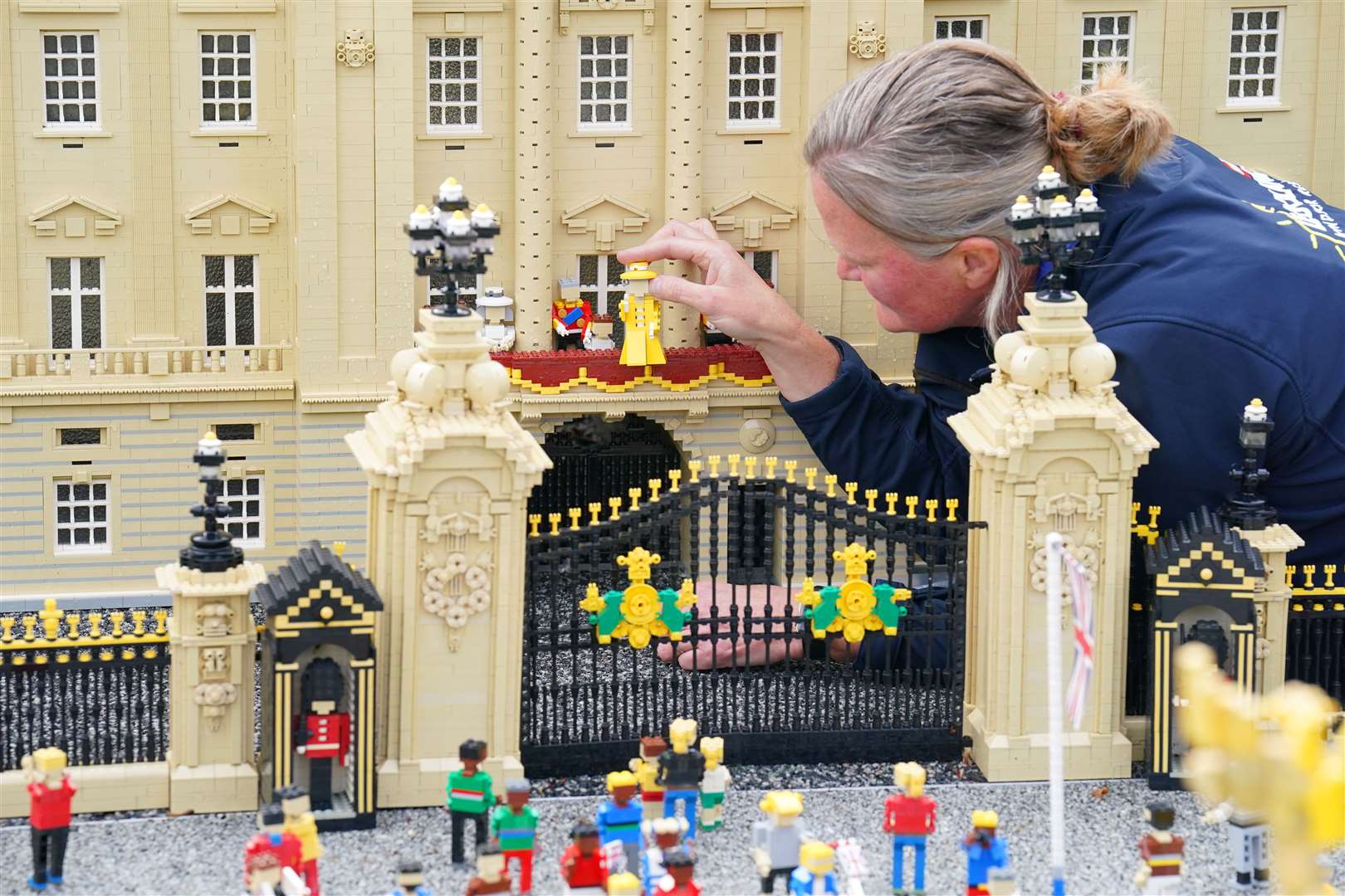 Model maker Paula Young places a Lego replica of the Queen in a display replicating the balcony scene at Buckingham Palace (Jonathan Brady/PA)