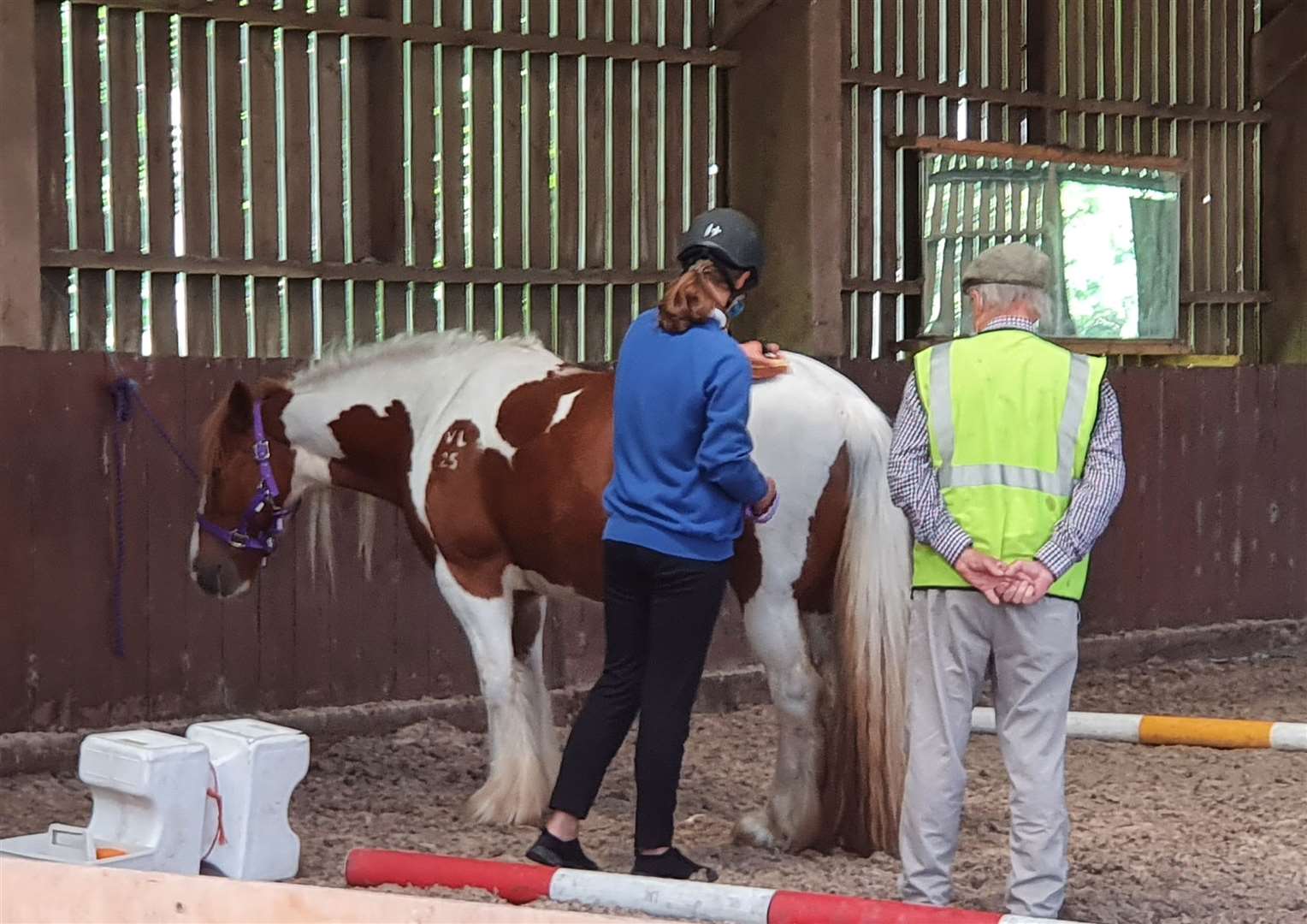 A young visitor learning about grooming with one of RDA's volunteer assistants.