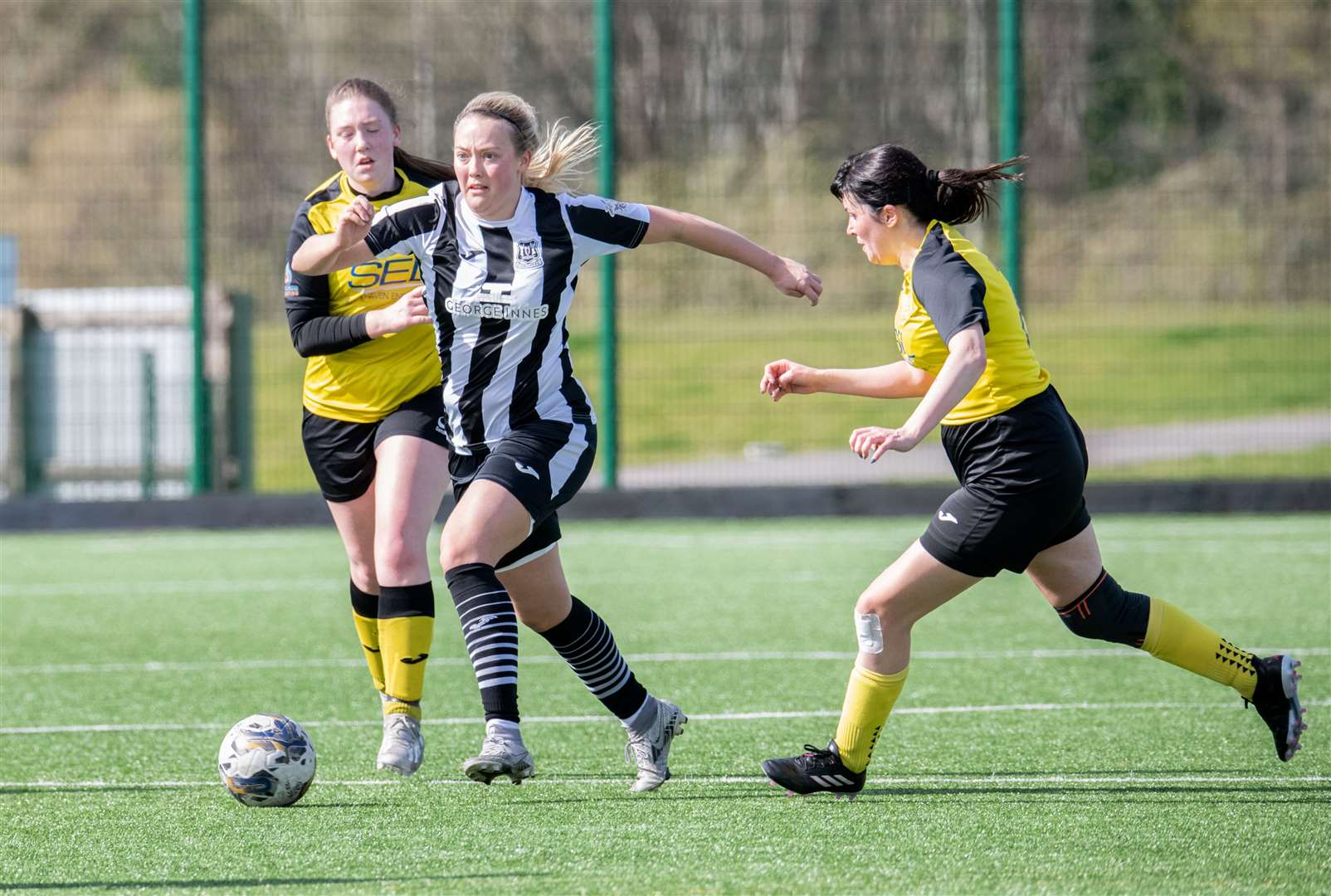 Elgin City's Charlotte Worthing plays the ball away from a Stonehaven duo.Picture: Daniel Forsyth.