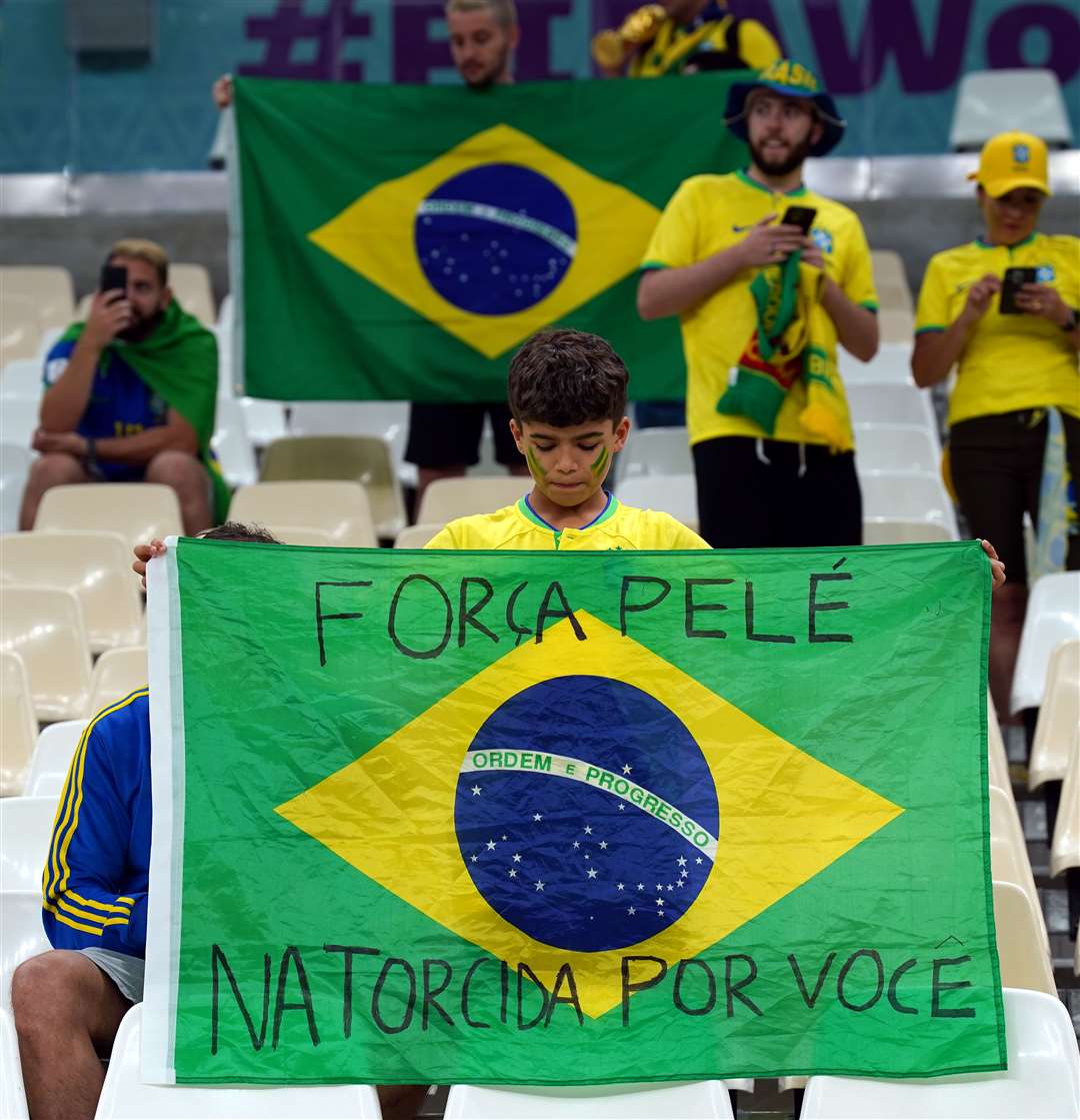 A young Brazil fan holds a flag dedicated to Pele in Lusail, Qatar (Peter Byrne/PA)