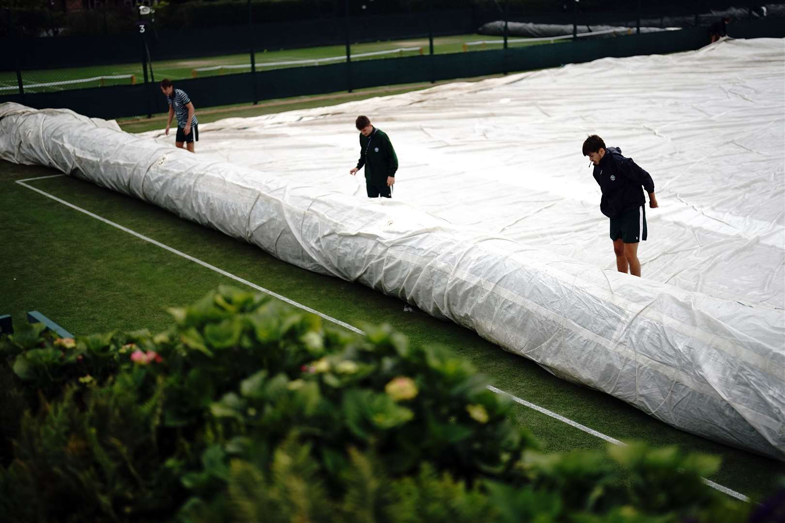 Ground staff cover the practice courts (Victoria Jones/PA)
