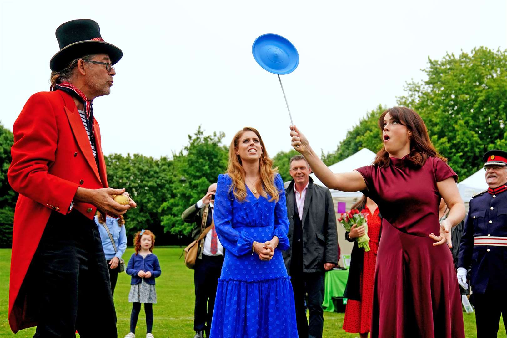 Princess Beatrice (centre) and Princess Eugenie trying their hand at plate spinning (Victoria Jones/PA)