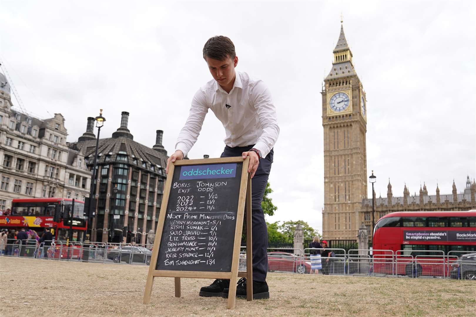 A man puts out a chalkboard in Parliament Square with the latest odds on when Boris Johnson will leave his post and who will replace him (Stefan Rousseau/PA)