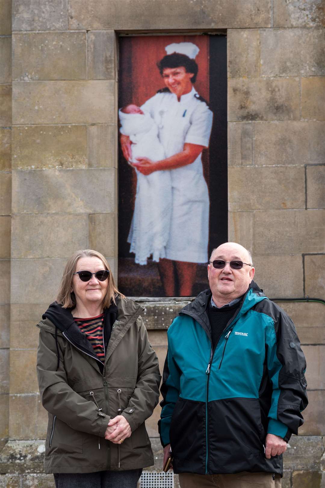 Heather Taylore and William McKinnon in front of a picture of their mum, nurse Winnie McKinnon.