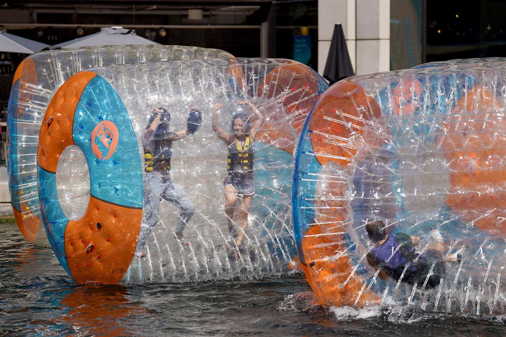 People enjoy the hot weather as they zorb on the canal at Paddington Basin in London (Joe Sene/PA)