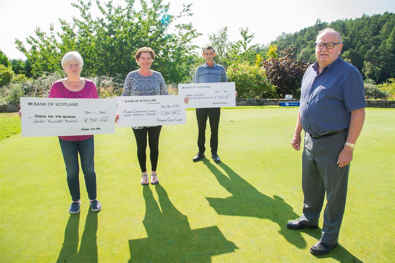 Flicker handing over cheques to Jan Thorne of Riding for the Disabled, Ali Noel of Forres Christmas Lights and Colin Mackay of Forres Golf Club on behalf of Forres in Bloom.