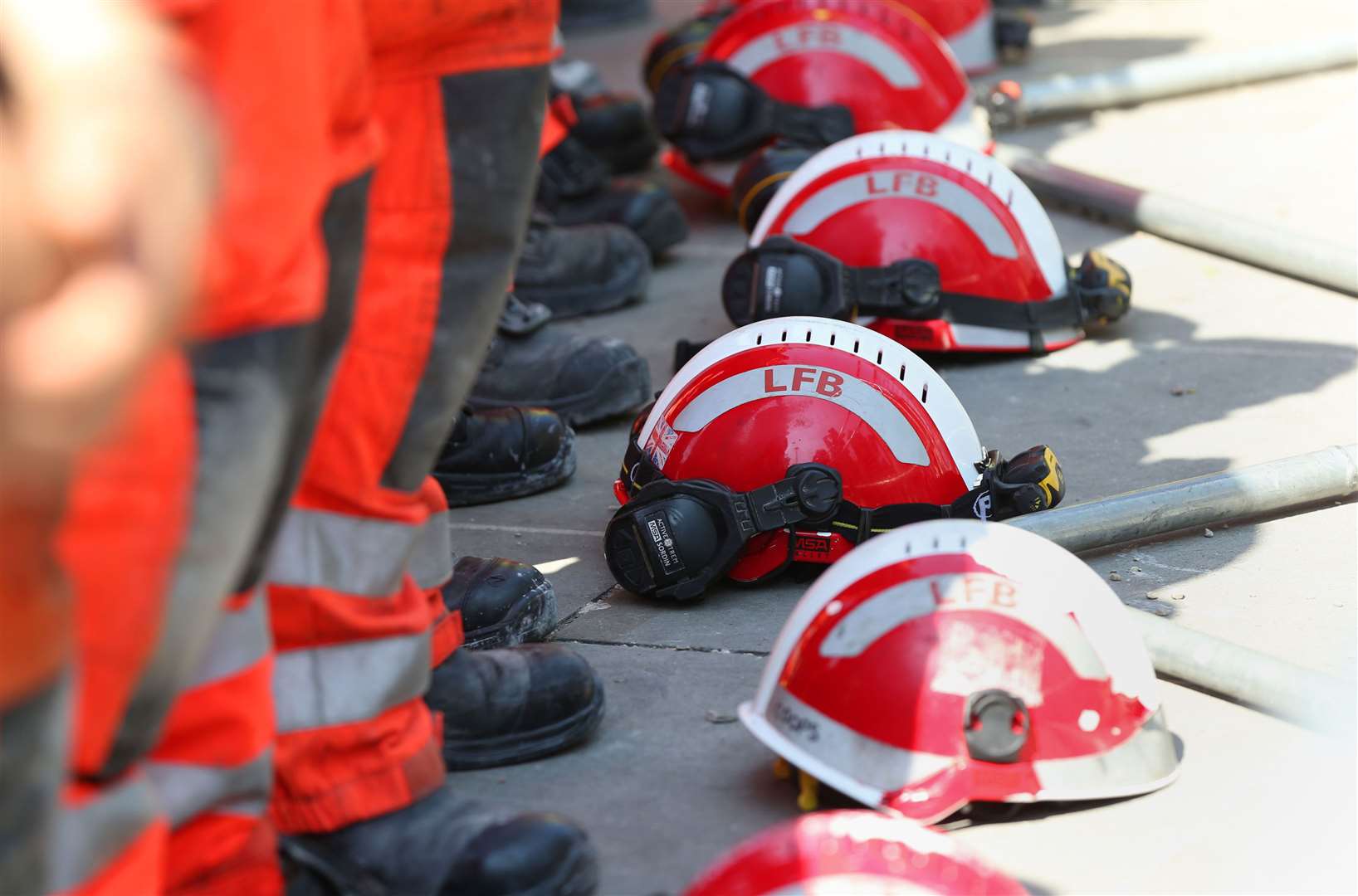 Firefighters lay their helmets on the ground during a minute’s silence near to Grenfell Tower (Jonathan Brady/PA)