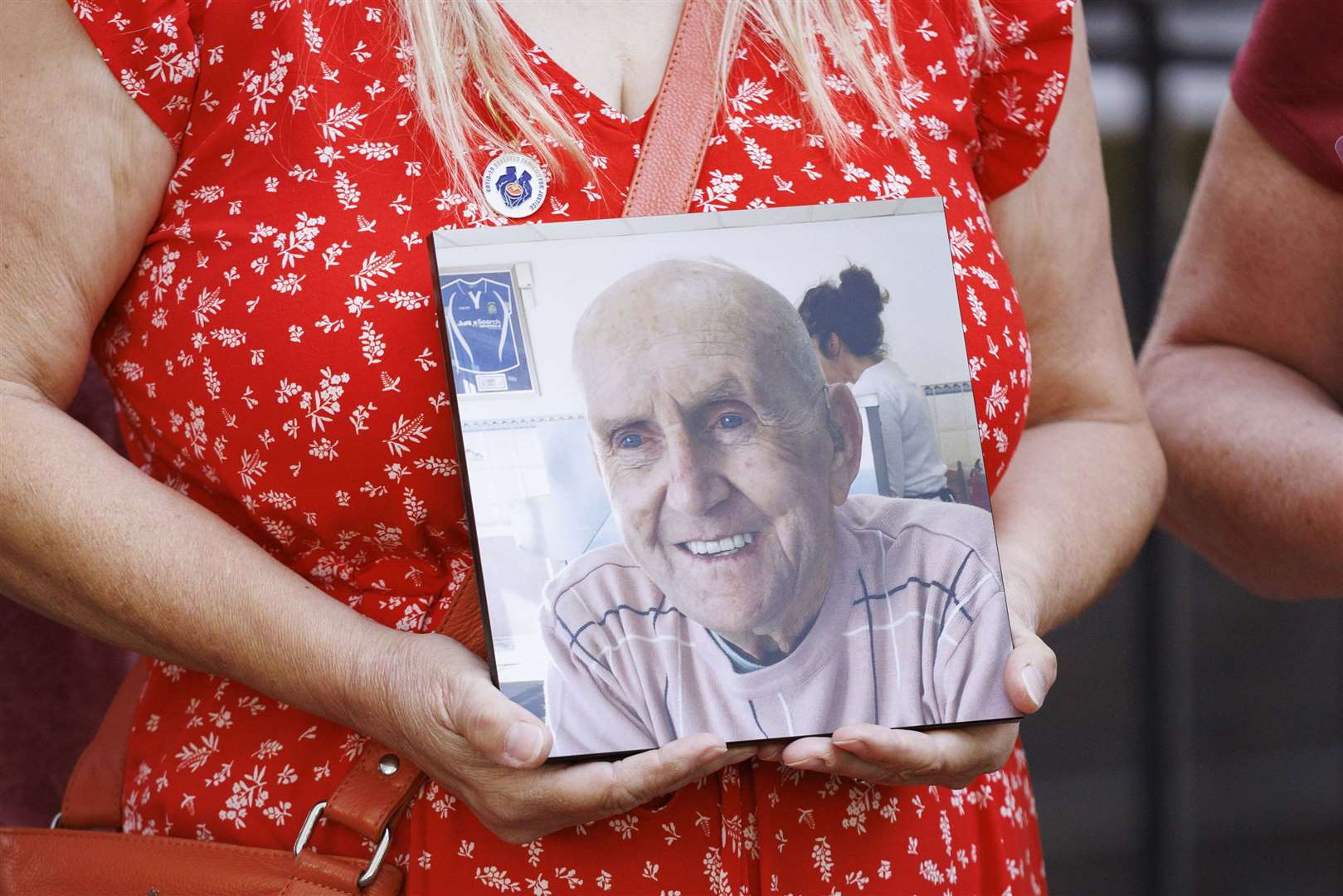 People hold pictures of loved ones lost during the pandemic, outside the UK Covid-19 Inquiry (Belinda Jiao/PA)