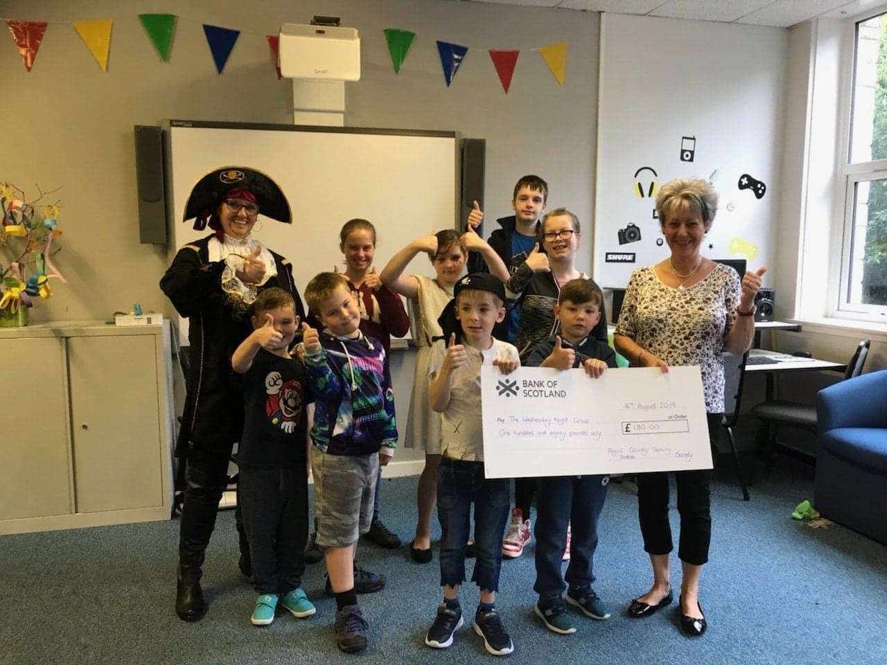 Christine Grant dropped in that morning with a special surprise of £180 which was raised by the Royal Scottish Country Dancing Society at their summer dance where raffles were sold, proceeds going to the Wednesday Night Group! Accepting the cheque (left to right) are Irene Muircroft (aka Jack Sparrow!), Aiden Dey, Elizabeth Quinn, Ruairidh Fraser, Hayden Robertson, Nicola Quinn and Mason Mawhinney are with Christine Grant in the photo.
