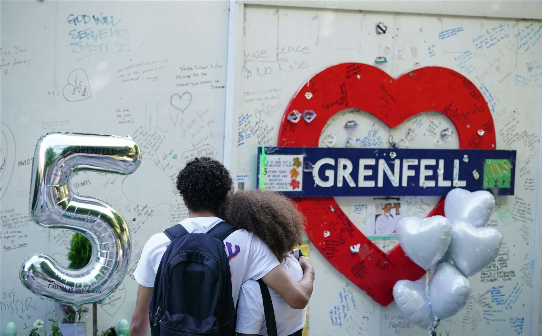 Members of the public took a moment to look at the memorial at the base of Grenfell Tower (Dominic Lipinski/PA)