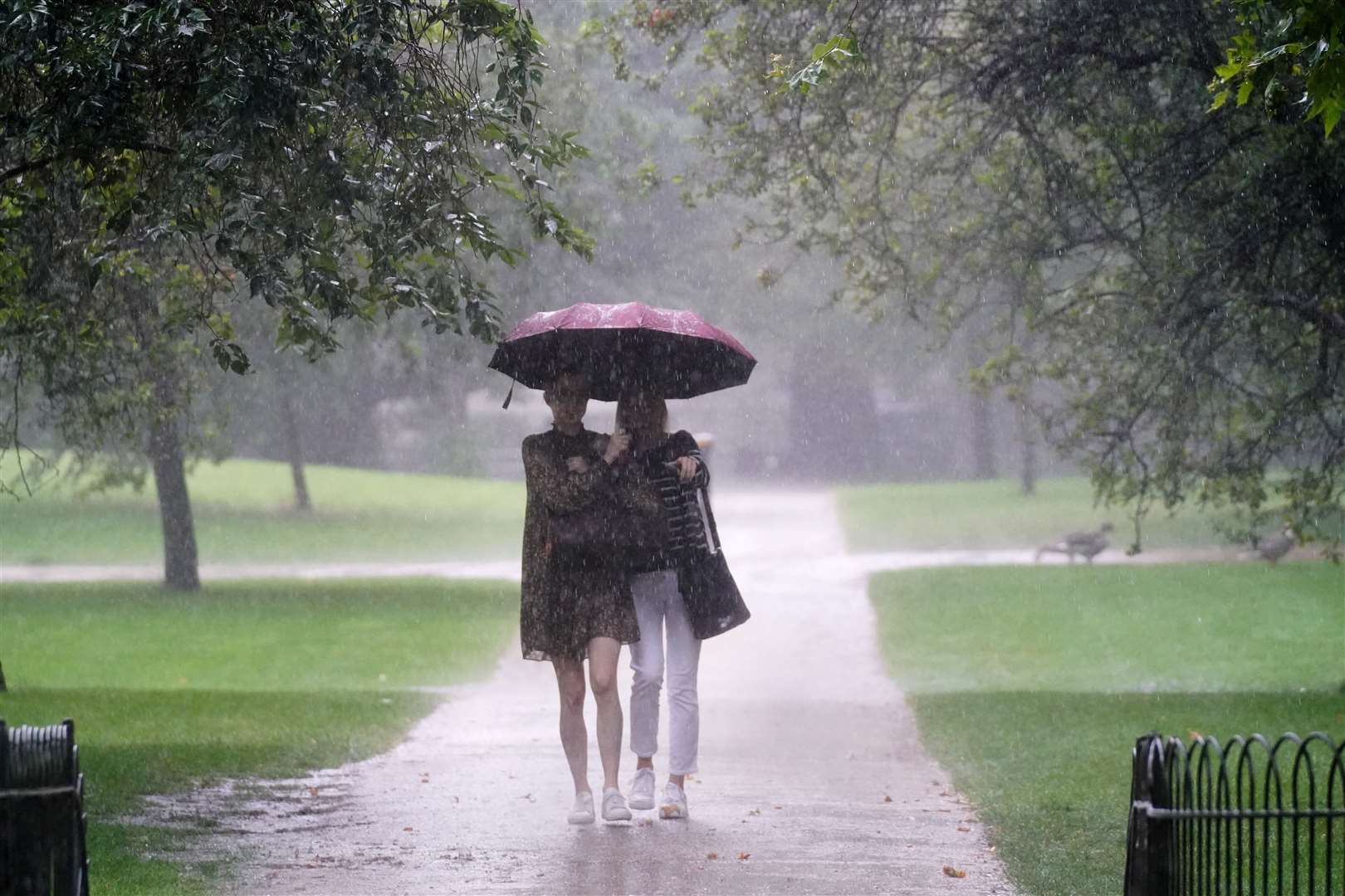 Two women walk through heavy rain in St James’s Park in central London (Victoria Jones/PA)