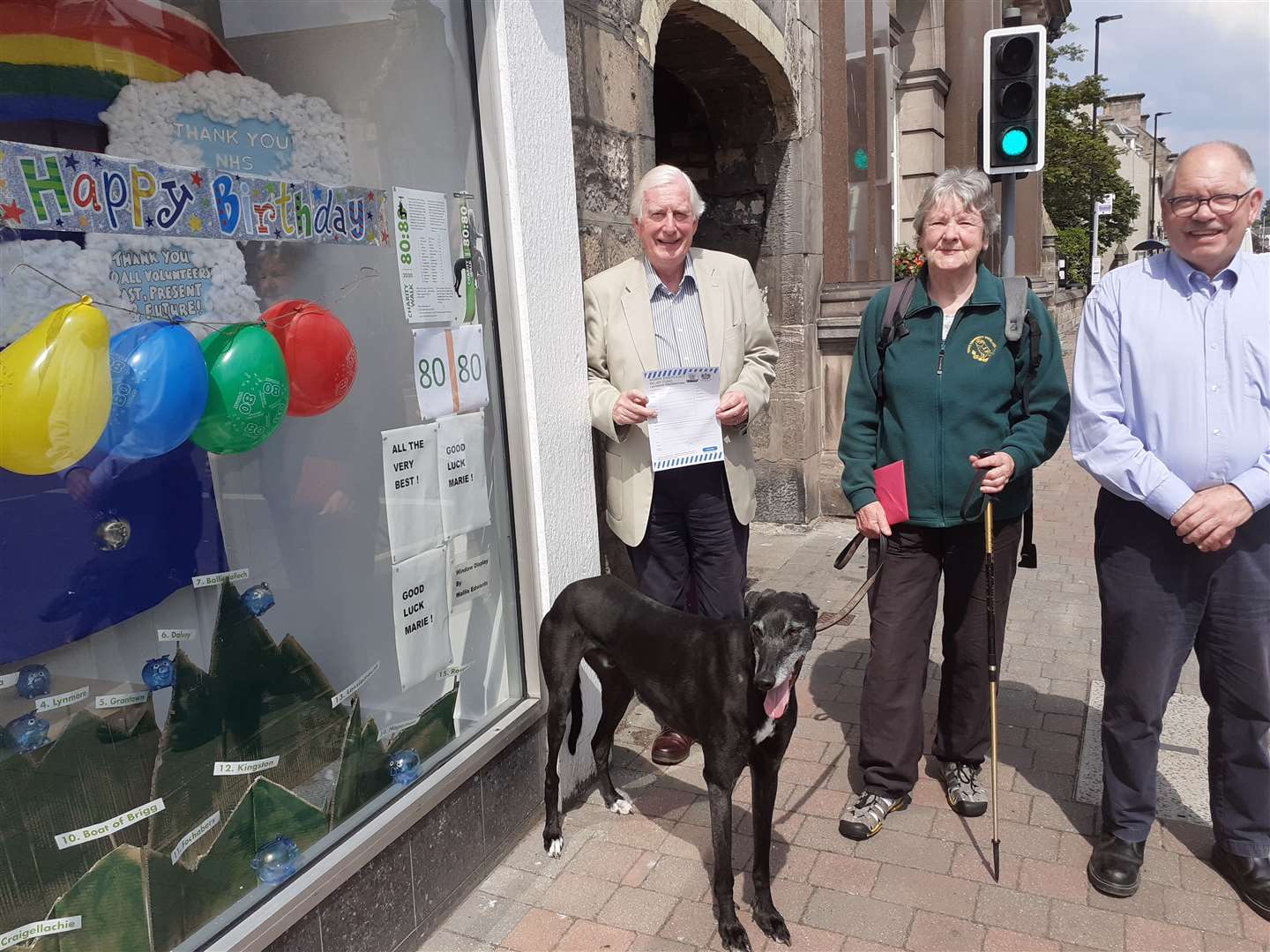 Moray Emergency Relief Fund trustees Major General Seymour Monro and Alan James with Marie Jacques and Ziggy, admiring the window display at Moray Firth Credit Union.