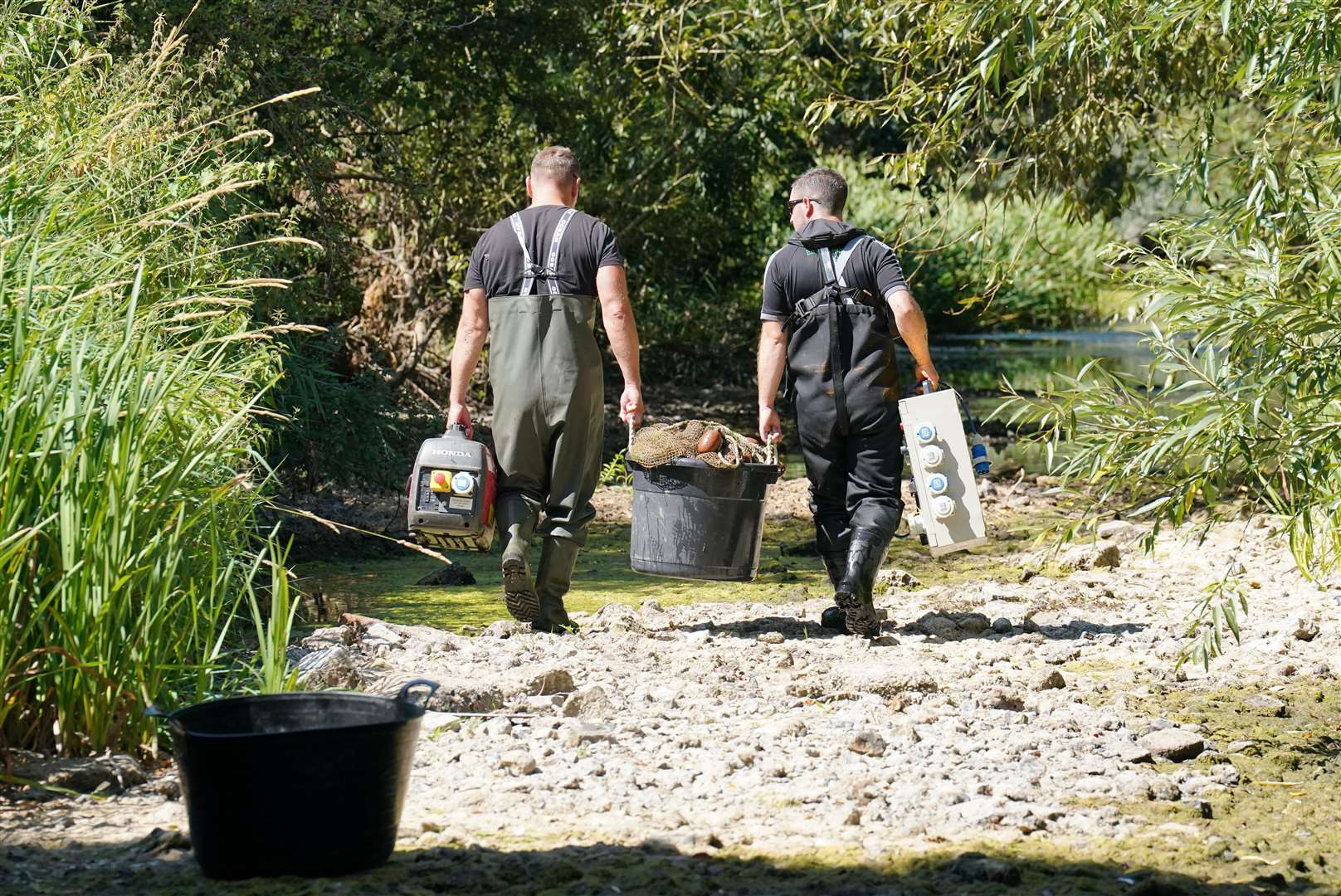 Fisheries officers from the Environment Agency remove equipment used to rescue fish from a drying pool of the River Mole (Jonathan Brady/PA)