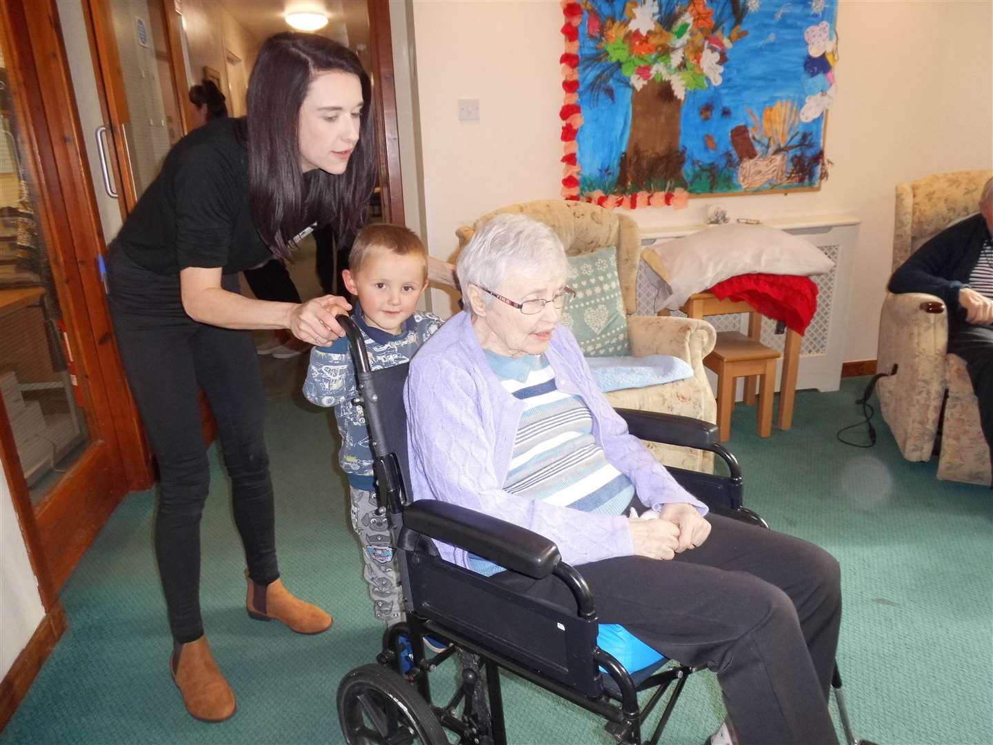 Reece Stephenson (4) helping to push a resident in her wheelchair.