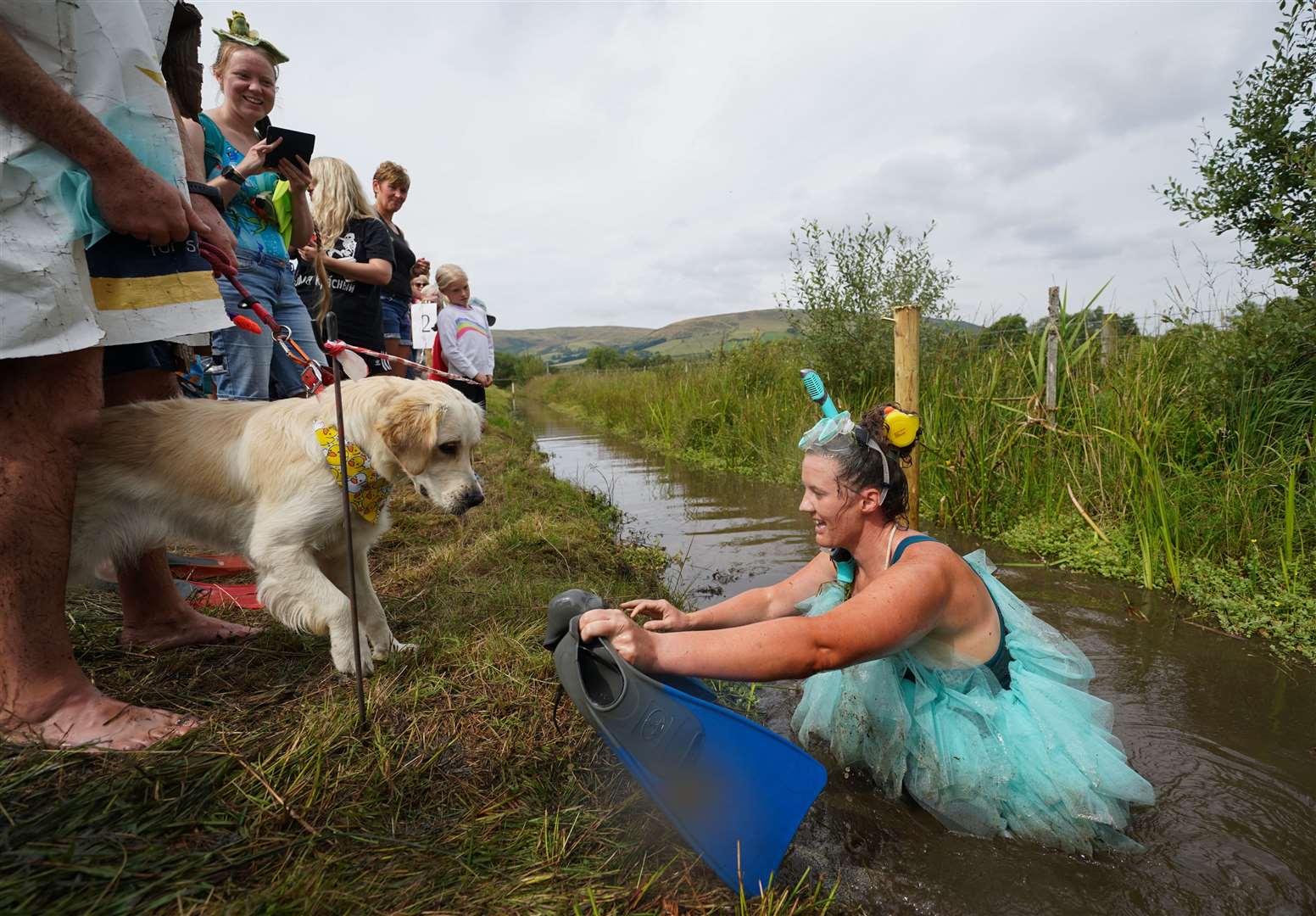 Louise Wild is greeted by her dog after taking part in the Rude Health World Bog Snorkelling Championships at Waen Rhydd peat bog in Llanwrtyd Wells, Wales (Joe Giddens/PA)