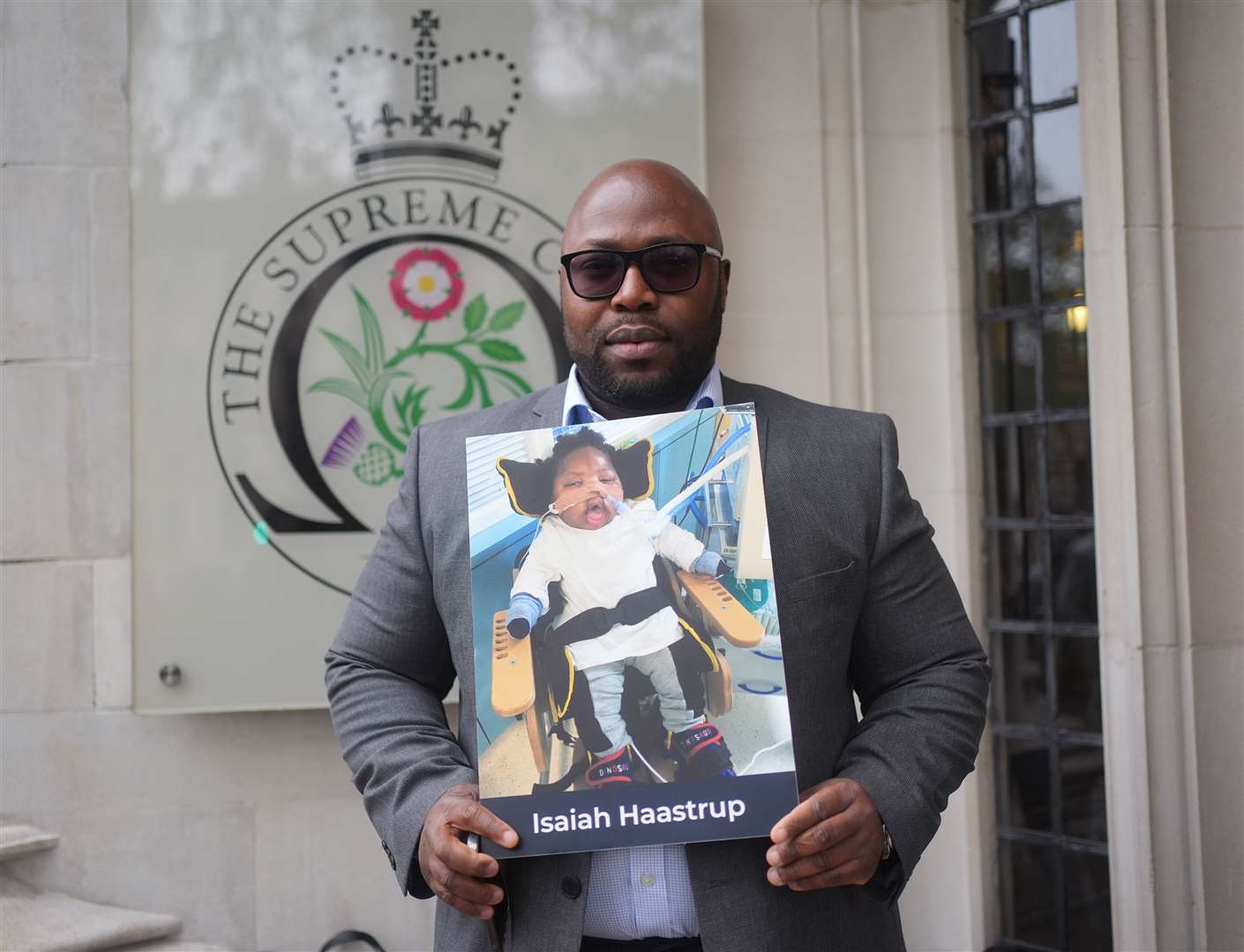 Lanre Haastru hold a picture of his son, Isaiah Haastrup, outside the Supreme Court (Yui Mok/PA)