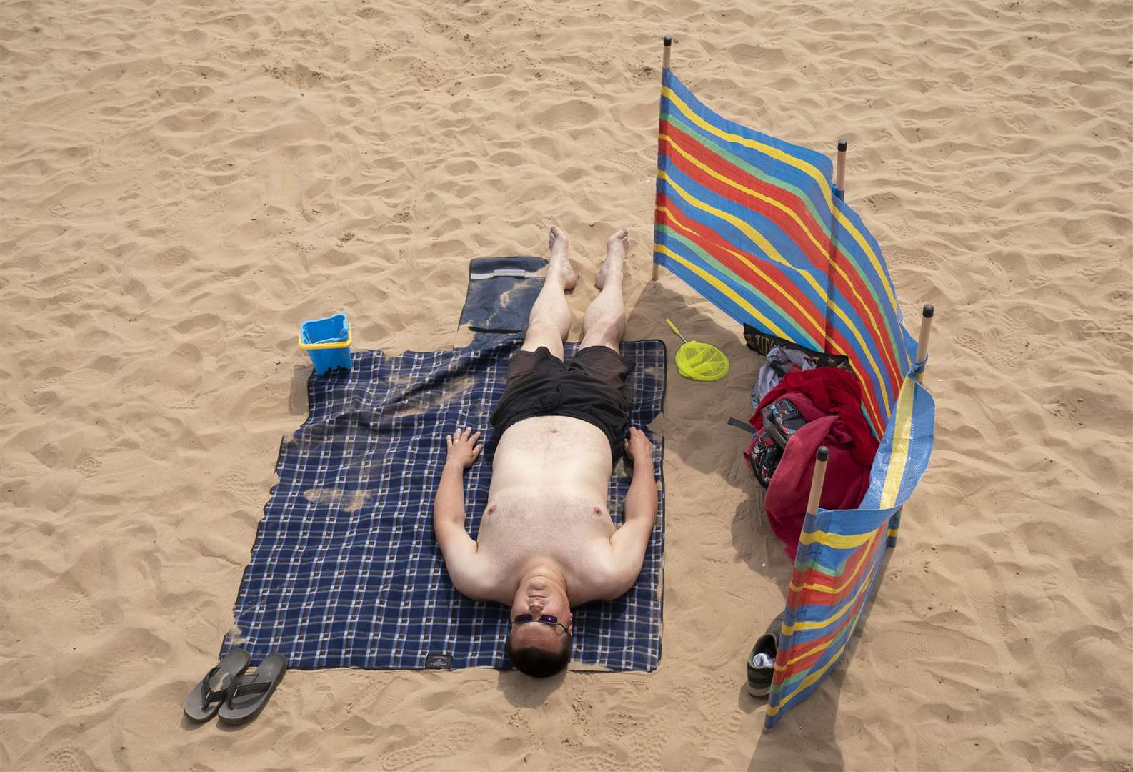 A man sunbathes as he enjoys the hot weather on Bridlington beach in Yorkshire (Danny Lawson/PA)