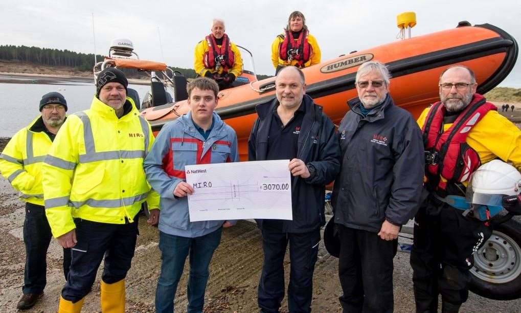 Zander (front left) presenting a cheque for £3070 to the volunteer team at Findhorn that helped save his life. (In the boat) crew members Shaun Burns and Claire Weller, (left to right) shore support volunteers Jock McEwan and Colin Jamieson, crew member Alastair MacDonald, MIRO secretary/treasurer Keith Parker and MIRO crew member Steve Leslie. Picture by Morven Mackenzie.