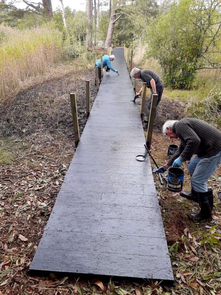 The boardwalk is painted with rubberised paint by (from left) Mike Sutherland, Brian Higgs and Richard Jordan.