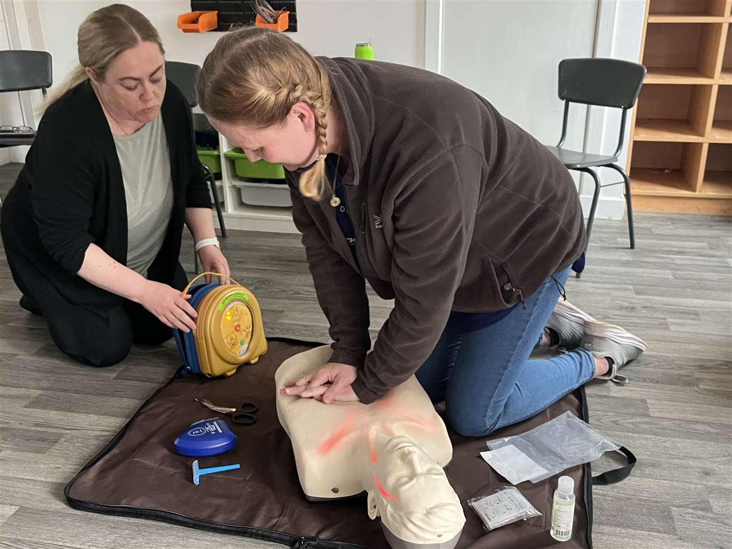 KCCKC committee member Tracy McBay (left) and parent Louise McNeill trying to resuscitate the individual using the defibrillator.