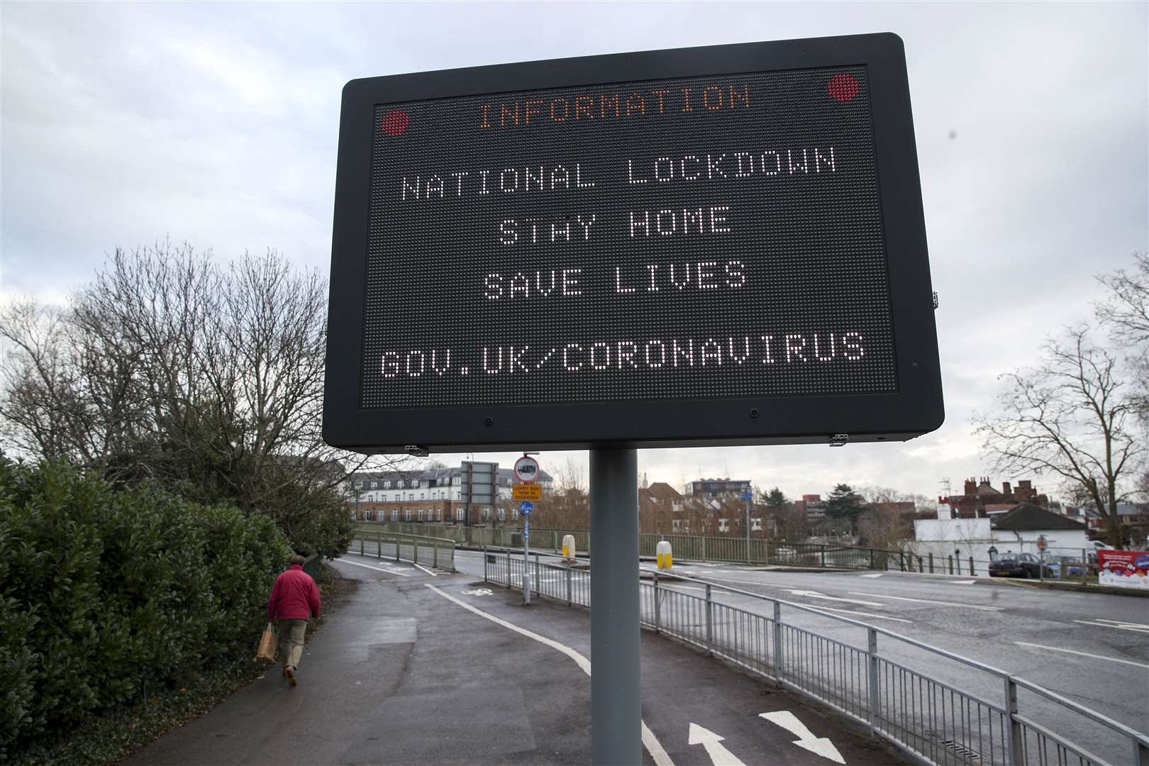 A man passes an information sign notifying people about the national lockdown (Steve Parsons/PA)