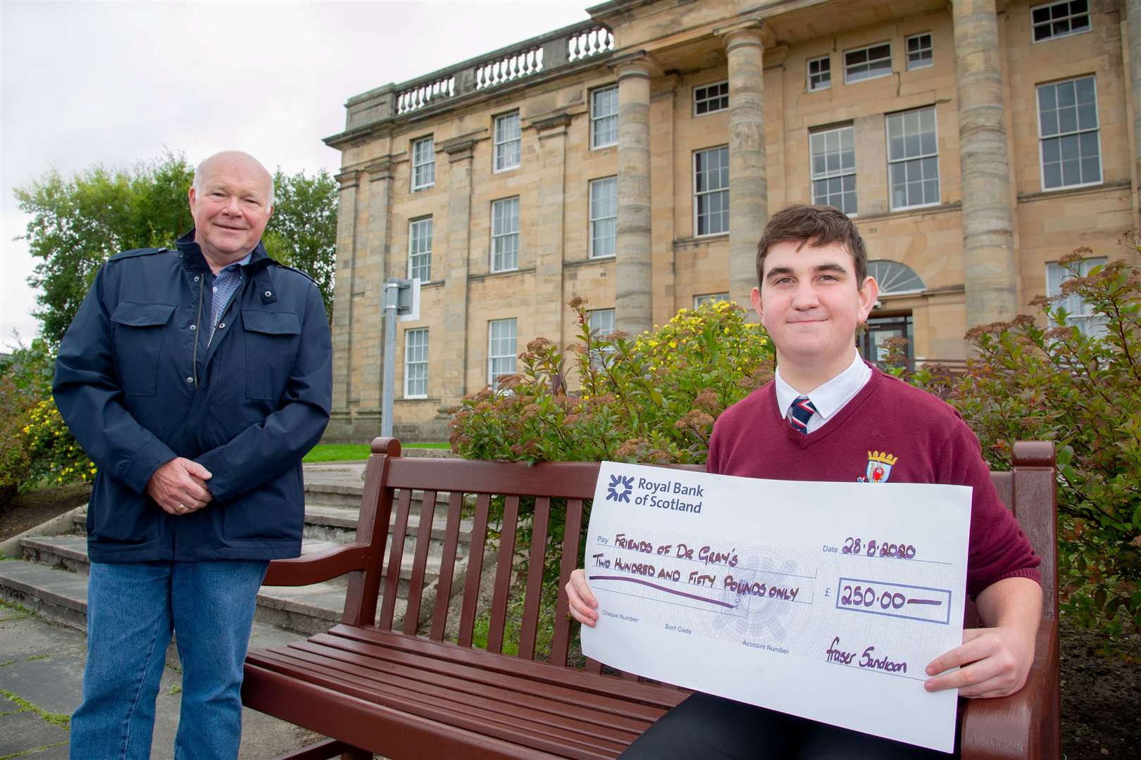Fraser Sandison, a sixth-year pupil at Elgin Academy, hands over a cheque to Friends of Dr Gray's committee member Dr Ken Brown outside the Elgin hospital.