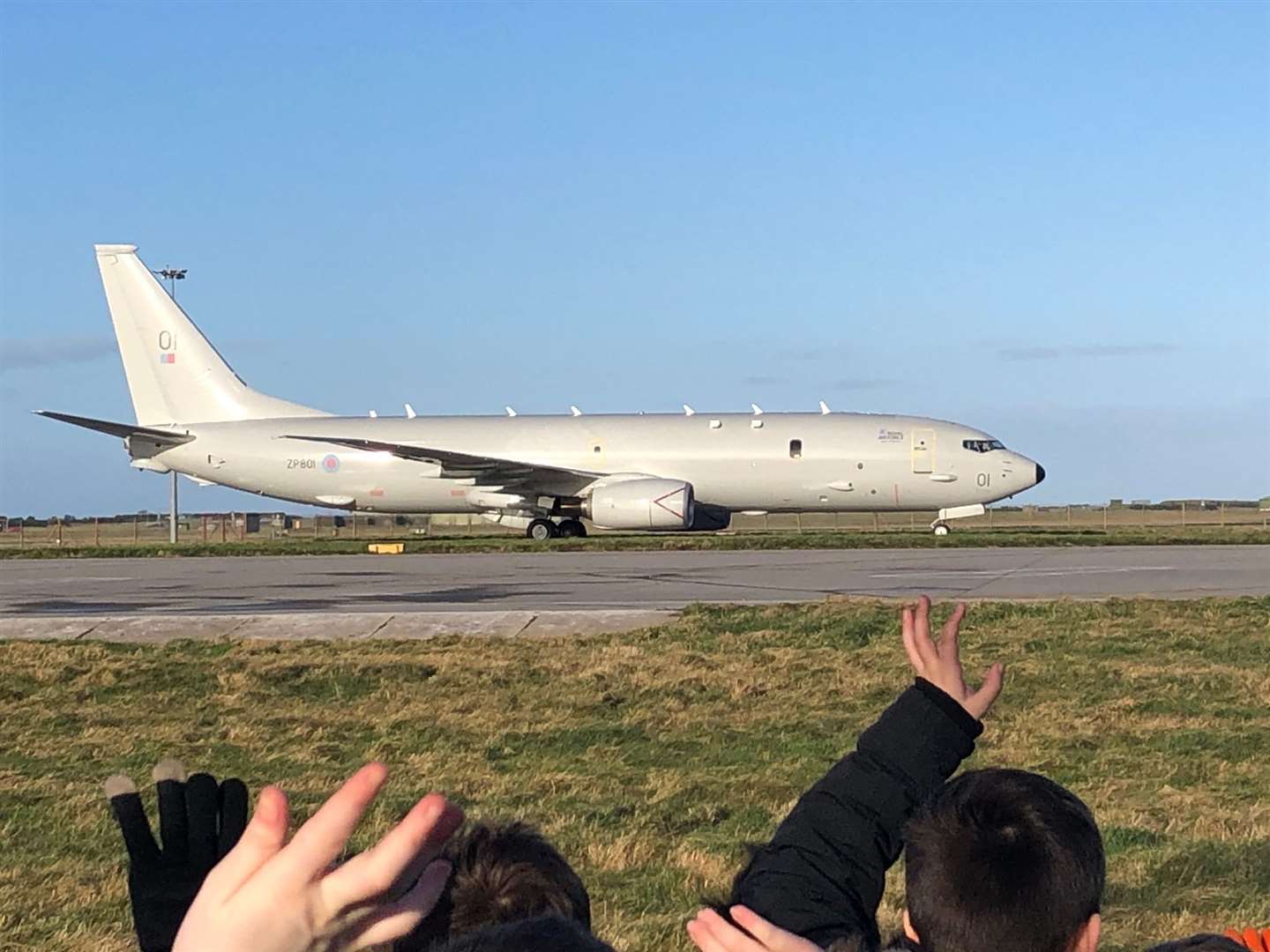 Kinloss pupils waving at the new aircraft as it lands on a runway near the village.