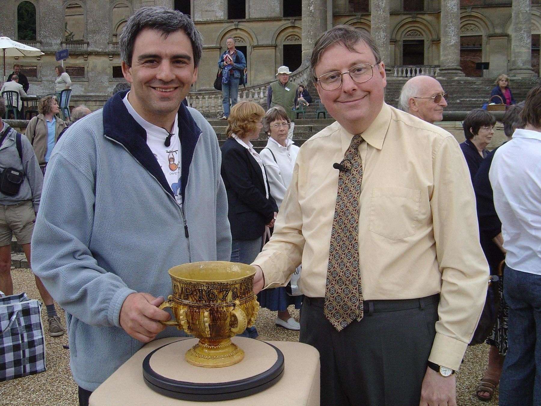 Antiques expert John Sandon, right, with the 17th century slipware cup he valued on Antiques Roadshow (BBC/PA)