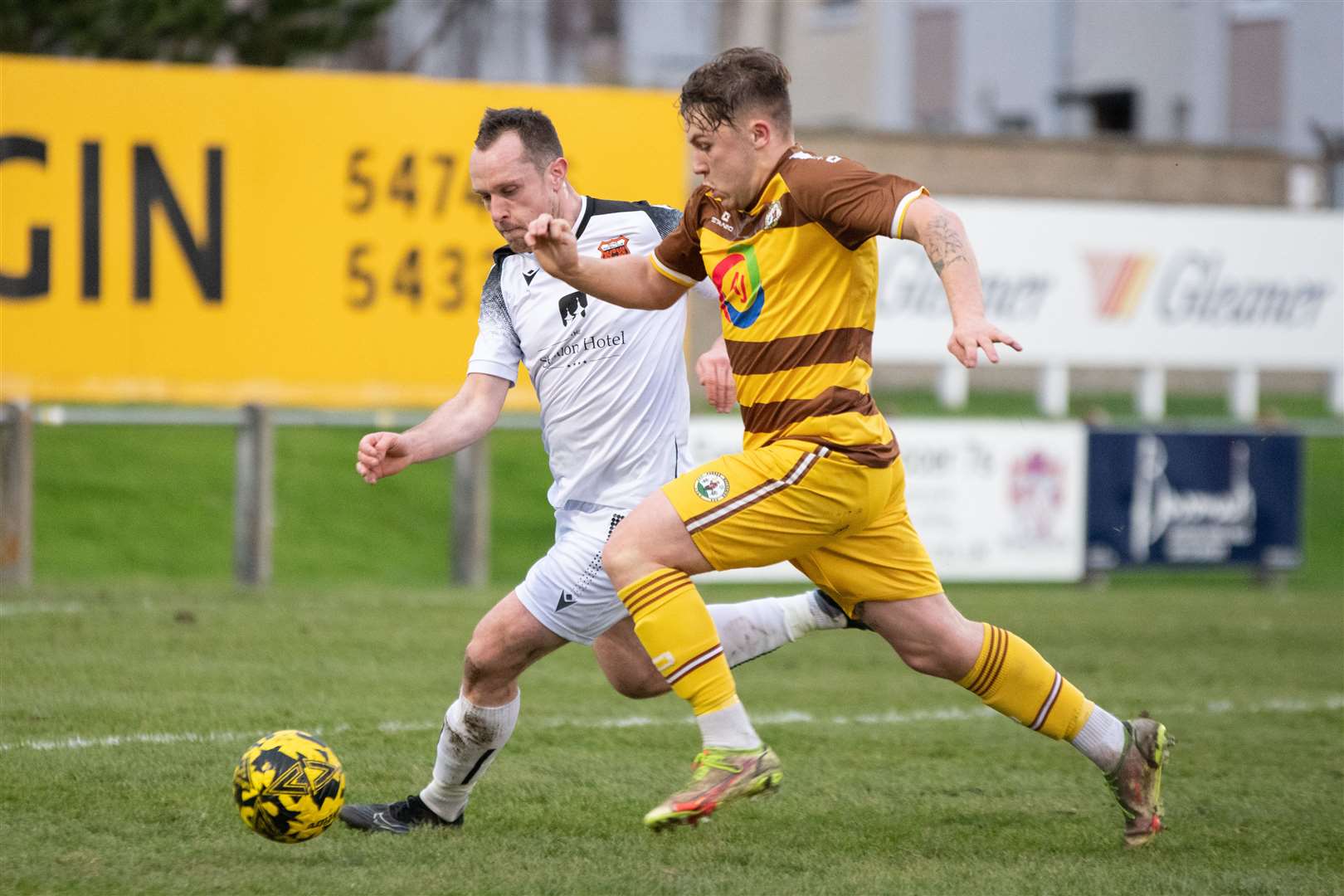 Forres forward Shaun Morrison charges in in a bid to win the ball from Rothes centre back Charlie MacDonald. ..Forres Mechanics FC (0) vs Rothes FC (1) - Highland Football League 23/24 - Mosset Park, Forres 25/11/2023...Picture: Daniel Forsyth..