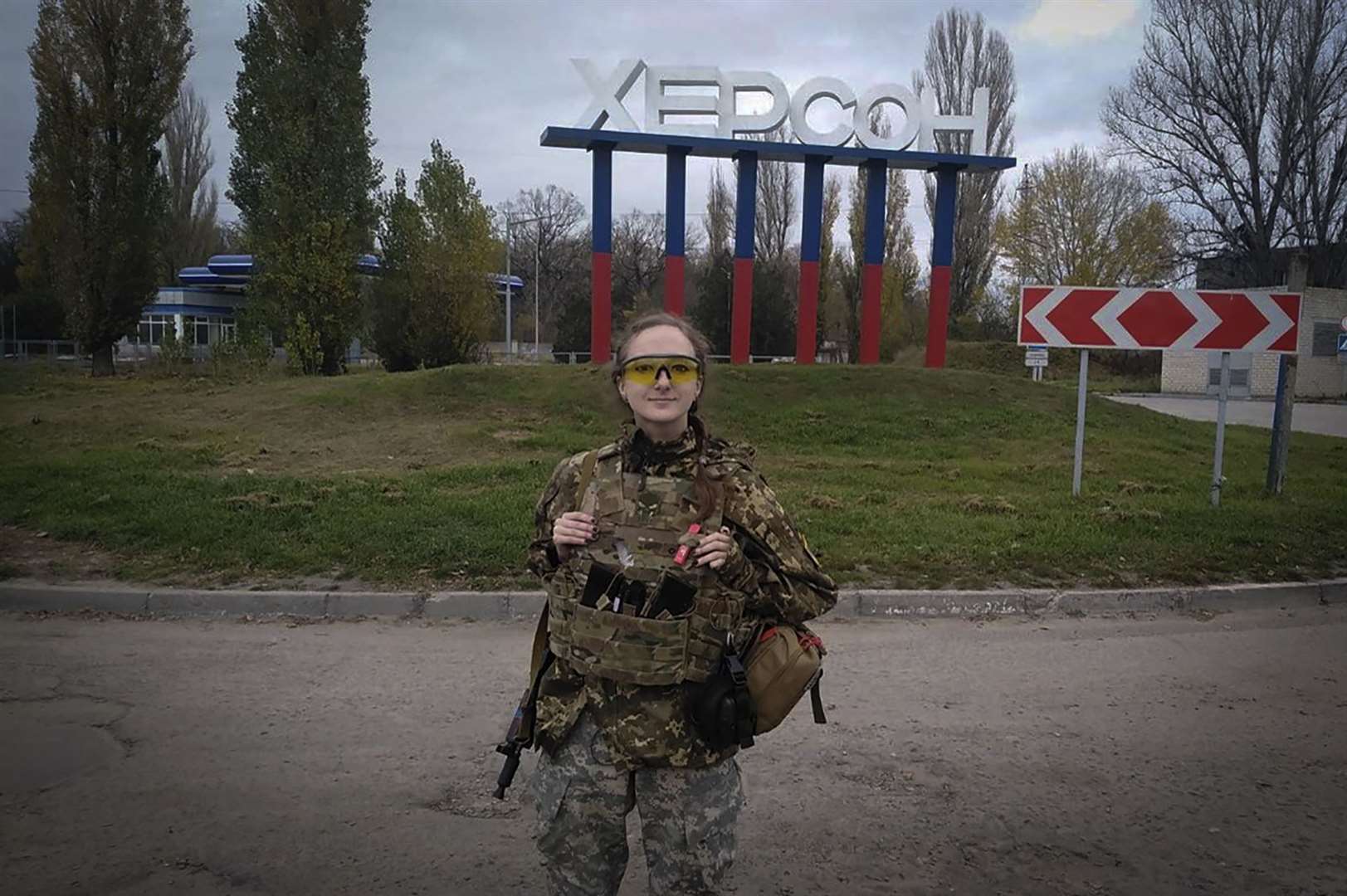 A female Ukrainian soldier poses for a photo against a Kherson sign in the background (Dagaz/AP)